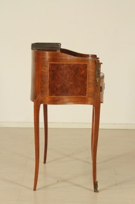 Scrittoio da centro, scrittoio dalla linea mossa.cassetto sotto-piano, piano estraibile, inserto in pelle, vani a giorno, cassettini sagomati con pianetto in marmo. Riserve a marquetterie e fregi.